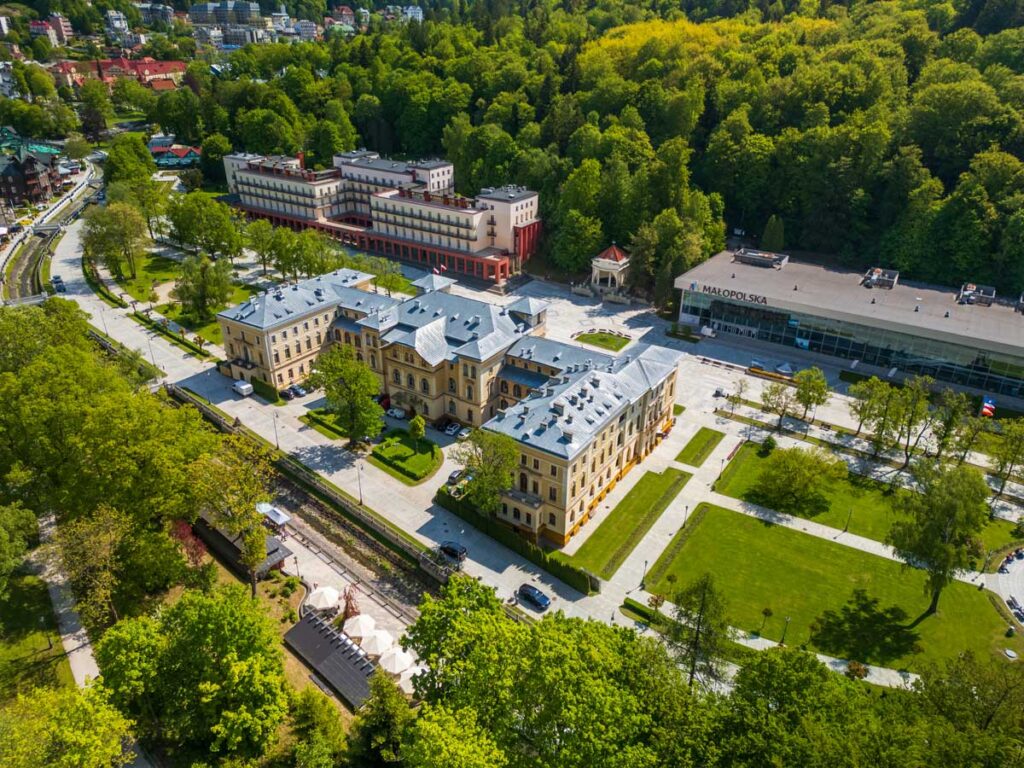 Widok z lotu ptaka na położony przy deptaku budynek w stylu neorenesansowym, otoczony zielenią. Stary Dom Zdrojowy w Krynicy-Zdroju.