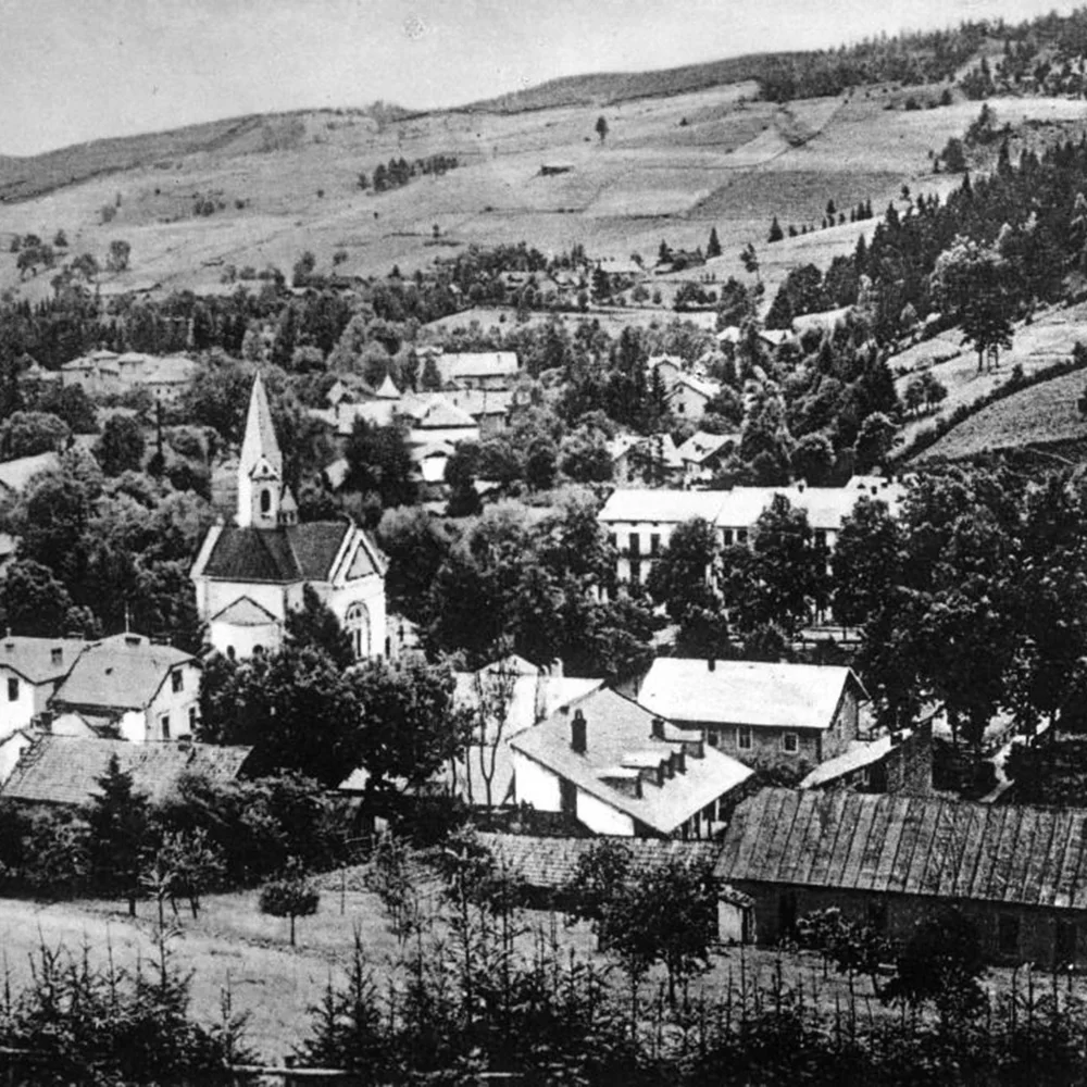 Archiwalne, czarno-białe zdjęcie Krynicy-Zdrój, widok na budynki i kościół otoczone drzewami.